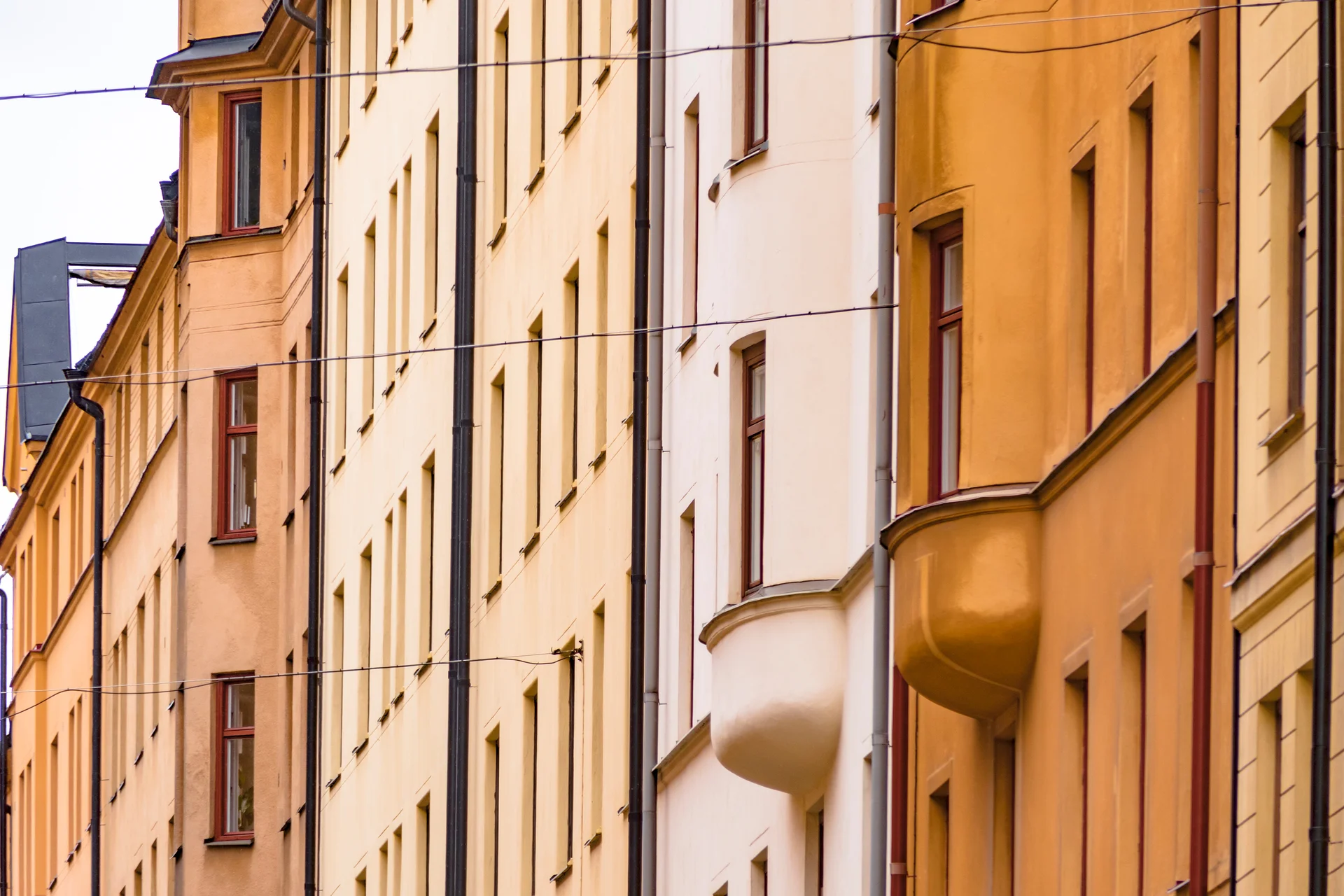 Gulrosa och vita putsfasader med fönster och runda balkonger, sedd underifrån.